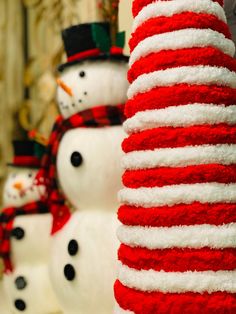 two snowmen are standing next to each other in front of red and white christmas decorations