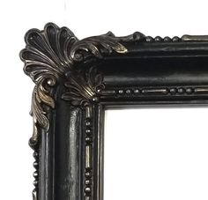 an ornate black framed mirror on a white wall