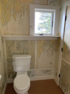 a white toilet sitting in a bathroom next to a window with a map on it