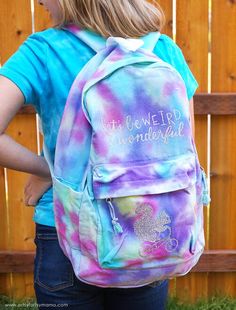 a girl wearing a tie dye backpack that says, let's be weird and wonderful