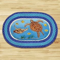 a blue rug with two sea turtles and fish on the bottom, in front of a wooden floor