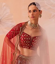 Elevate your elegance with this exquisite Red Embroidered Bridal Lehenga set, designed with a mesh overlay and a comfortable crepe lining. The rich red lehenga features intricate floral and geometric embroidered motifs in vintage gold and embellished gold hues, adding depth and sophistication to the design. Complementing the lehenga, the embroidered blouse brings a regal touch with its meticulous craftsmanship. Completing the look is a scalloped, hand-embroidered dupatta that drapes beautifully, enhancing the outfit's luxurious appeal. Perfect for a bride or bride-to-be on your special day. Composition : Blouse, Lehenga & Dupatta : Mesh with Crepe Lining Care: Dry Clean Only and Vacuum Storage This product can be customized for sleeves, length and colour Delivery : 4-6 weeks as the product