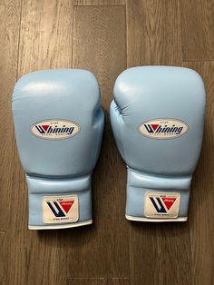 two blue boxing gloves sitting on top of a wooden floor