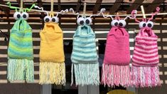 four knitted scarves hanging on a clothesline with eyeballs and fringes