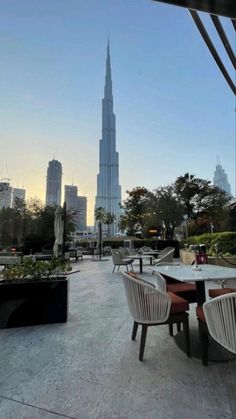 an outdoor dining area with chairs and tables in front of the burj building