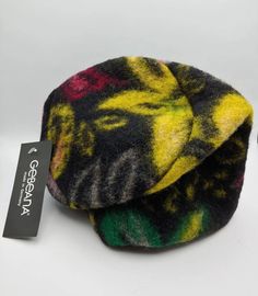 a multicolored hat sitting on top of a white table next to a tag