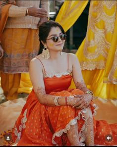 a woman sitting on the ground in an orange dress