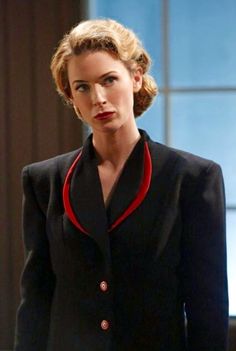 a woman in a black suit and red collared shirt