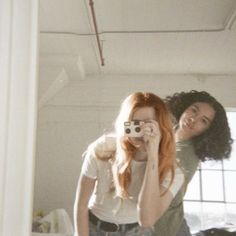 two women are taking pictures in the mirror