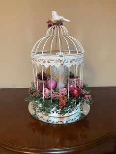 a white birdcage filled with ornaments on top of a wooden table