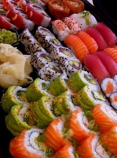 an assortment of sushi on display in a tray