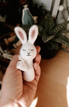 a person holding a stuffed animal in their hand on a table with other toys and plants