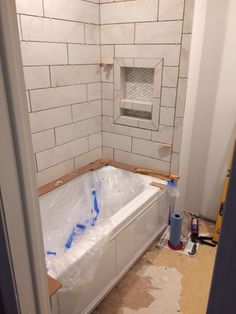 a bathtub being installed in the corner of a room with white subway tiles on the walls