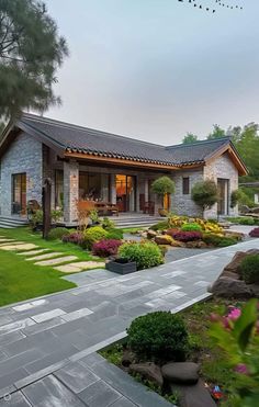 a house that is sitting in the middle of some grass and flowers on the ground