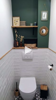 a white toilet sitting inside of a bathroom next to a shelf with pictures on it