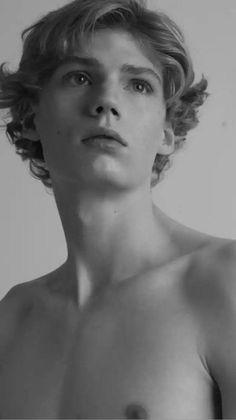 black and white photograph of a shirtless young man with curly hair looking at the camera