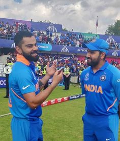 two men in blue uniforms standing next to each other on a field with people watching