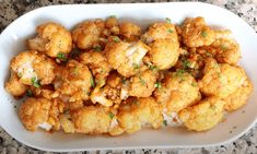 a white plate topped with fried cauliflower on top of a counter next to a knife