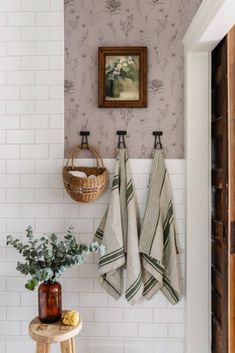 two towels hanging on the wall next to a potted plant and vase with flowers