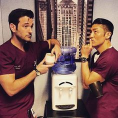 two men standing next to each other in front of a water dispenser