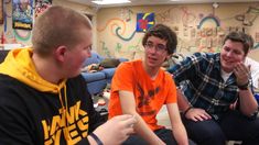 three young men sitting on the floor talking to each other