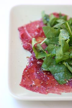 a white plate topped with greens and meat