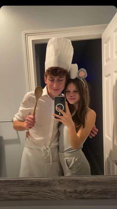 a man and woman taking a selfie in front of a mirror wearing chefs hats