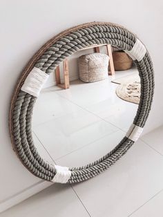 a round mirror sitting on top of a white floor next to a wooden shelf with baskets