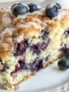 a close up of a piece of cake with blueberries and cream frosting on it