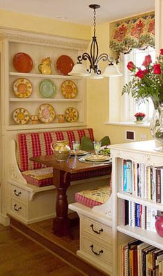 a dining room table and chairs with plates on the wall above them, along with bookshelves