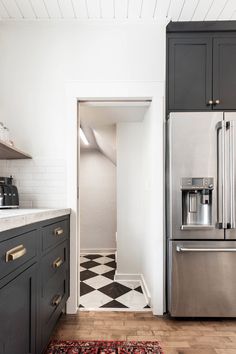 a kitchen with black and white checkered flooring, stainless steel appliances and cabinets