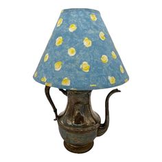 a blue lamp with yellow and white flowers on the lampshade is shown against a white background