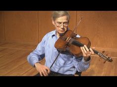 an older man holding a violin in his hands