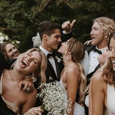 a group of people standing next to each other in front of some trees and flowers