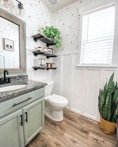 a white toilet sitting next to a sink in a bathroom under a window with plants on top of it