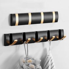 three black and gold striped hooks on a wall next to a towel rack with two towels