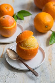 two oranges are sitting on plates with spoons