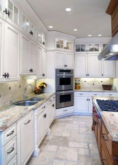 a large kitchen with white cabinets and granite counter tops, along with stainless steel appliances