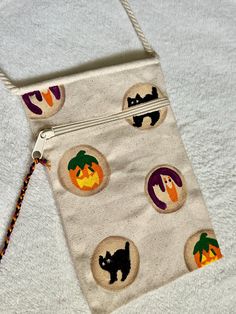 a white bag with halloween decorations on it and a string attached to the front pocket