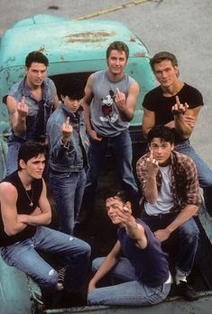 the young men are posing for a photo in front of an old blue pickup truck