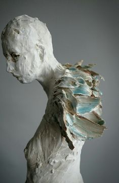 a white sculpture with blue and green paint on it's body, against a gray background