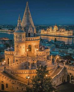 an aerial view of a castle in the middle of a city at night with lights on