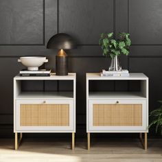 two white nightstands with wicker baskets on them against a black wall next to a potted plant