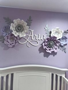 a baby crib with flowers on the wall and name above it that says aria