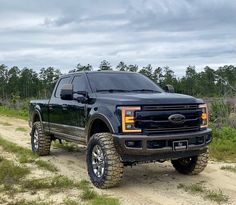 a black truck is parked on a dirt road