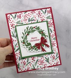 someone is holding up a christmas card with holly wreaths and red berries on it