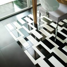 a white chair sitting on top of a black and white checkered floor next to a wooden table