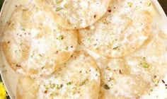 a white plate topped with crackers covered in cheese and seasoning next to yellow flowers