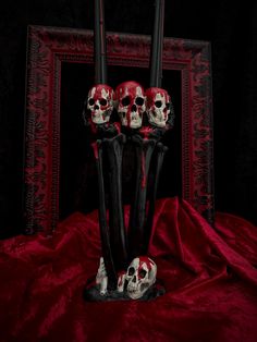 there are three skulls sitting in the middle of two tall black vases on a red cloth