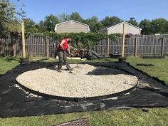 a man is shoveling gravel in his backyard area with a black tarp over it